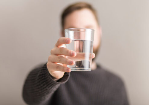 hombre sujetando vaso de agua purificada